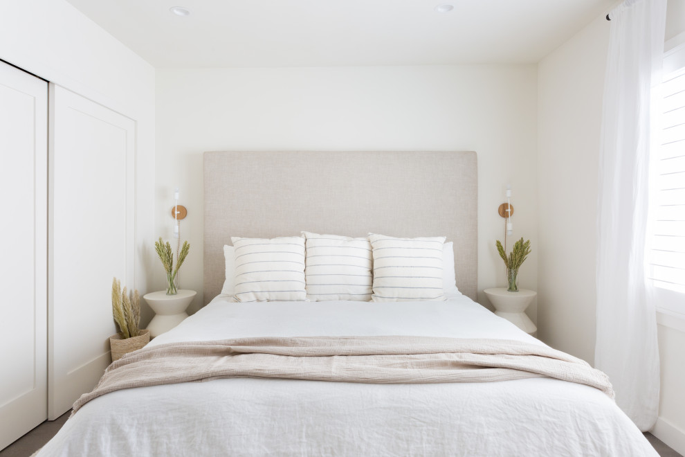 Ejemplo de dormitorio principal costero pequeño sin chimenea con paredes blancas, suelo de madera en tonos medios y suelo gris