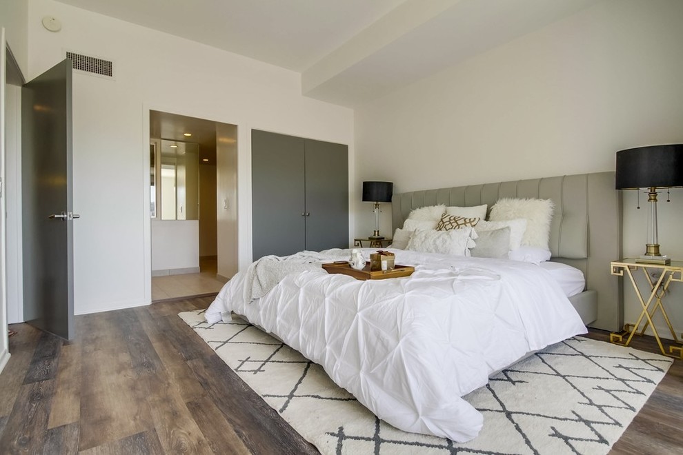 Imagen de dormitorio principal minimalista grande con paredes blancas y suelo marrón