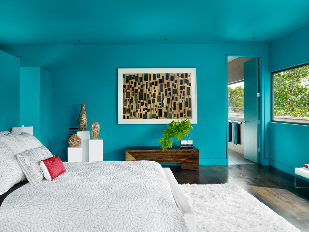 Cette image montre une chambre parentale design avec un mur bleu, parquet foncé et aucune cheminée.