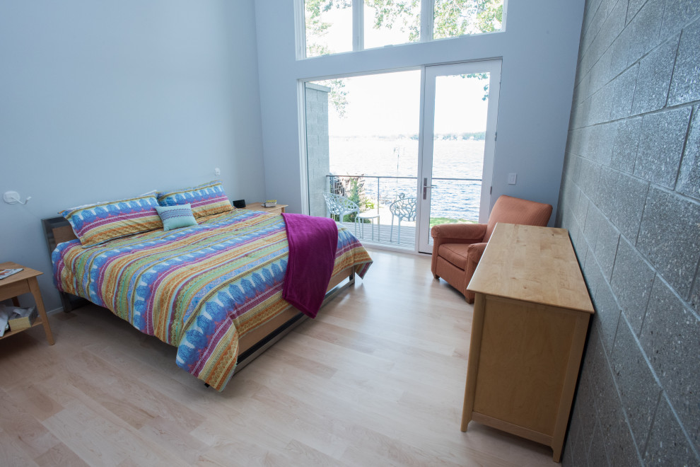 Modelo de dormitorio principal y abovedado actual de tamaño medio con paredes grises y suelo de madera clara