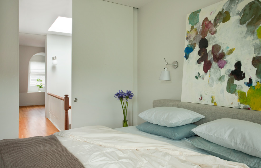 Foto de habitación de invitados minimalista de tamaño medio sin chimenea con paredes grises y suelo de madera clara