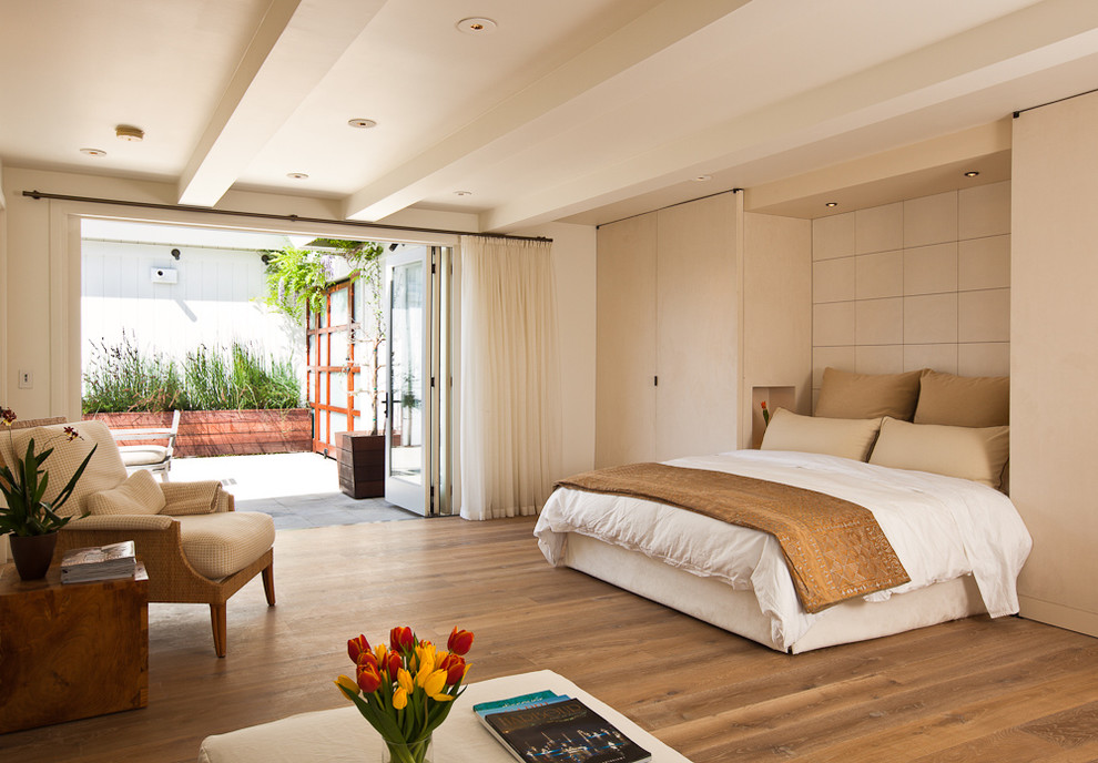 Cette image montre une chambre design avec un mur beige, un sol en bois brun et un sol marron.