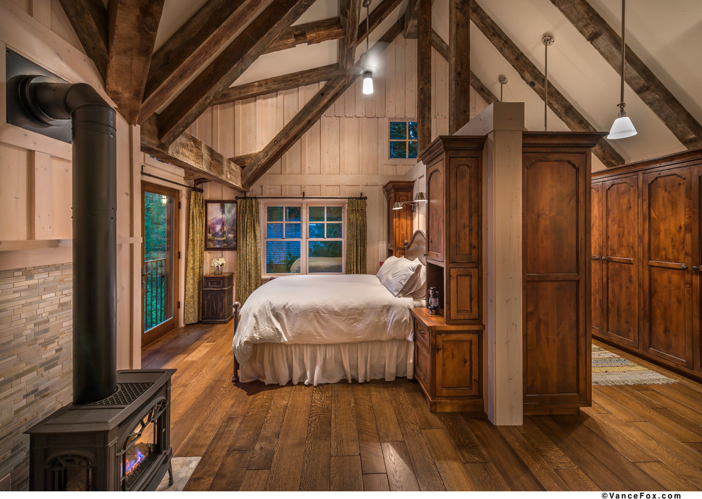 Idee per una grande camera matrimoniale country con pareti beige, pavimento in legno massello medio e stufa a legna