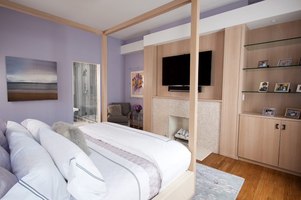 Klassisches Hauptschlafzimmer mit lila Wandfarbe, braunem Holzboden und Kaminumrandung aus Stein in New York