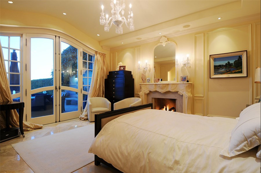 バンクーバーにある地中海スタイルのおしゃれな寝室 (ベージュの壁、ライムストーンの床、標準型暖炉、木材の暖炉まわり) のインテリア