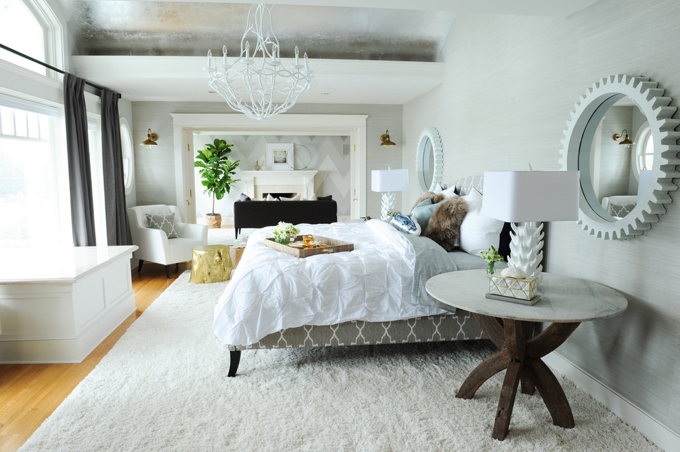Design ideas for a large coastal master bedroom in Vancouver with grey walls, light hardwood flooring, a standard fireplace, a stone fireplace surround and brown floors.