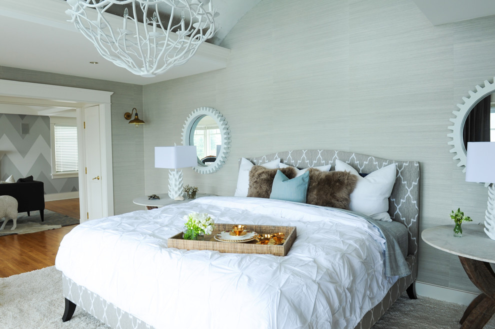 Inspiration for a large beach style master bedroom in Vancouver with grey walls, light hardwood flooring, a standard fireplace, a stone fireplace surround and brown floors.