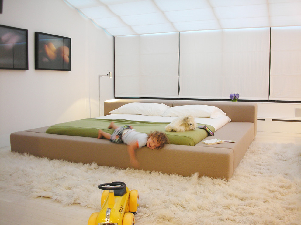 Example of a danish light wood floor bedroom design in New York with white walls
