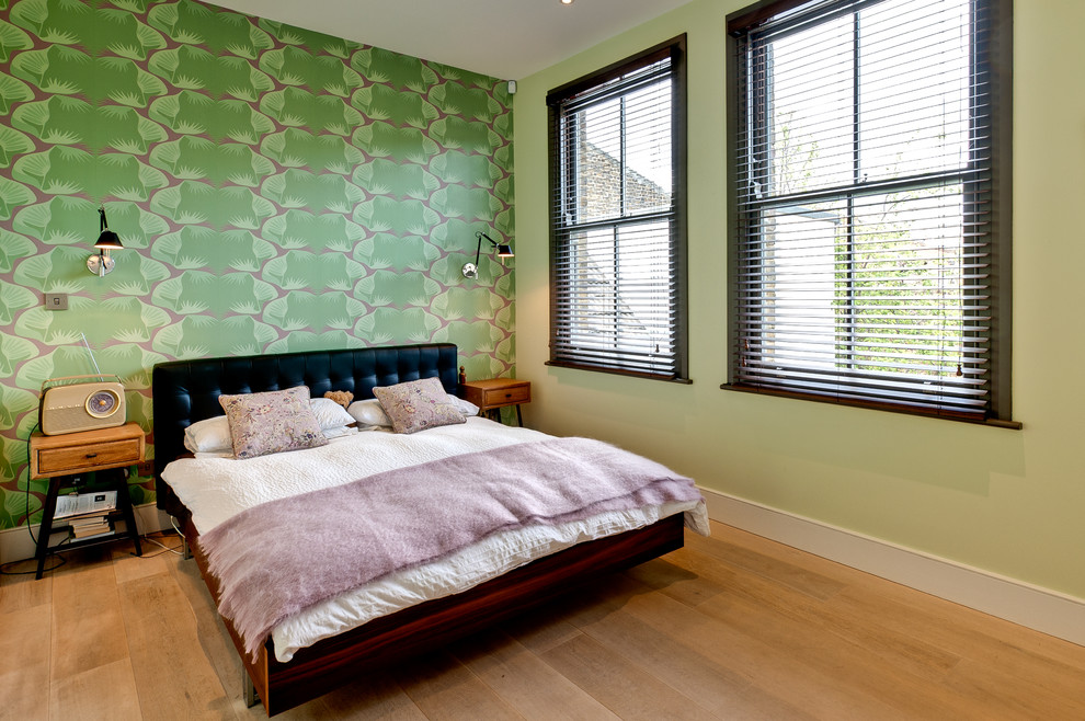 Inspiration for a bohemian master and grey and cream bedroom in London with green walls and light hardwood flooring.