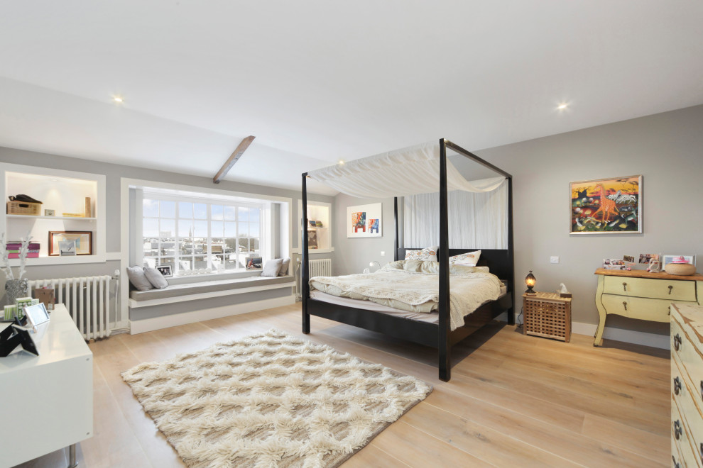 Modelo de dormitorio principal clásico renovado con paredes grises, suelo de madera clara y suelo beige
