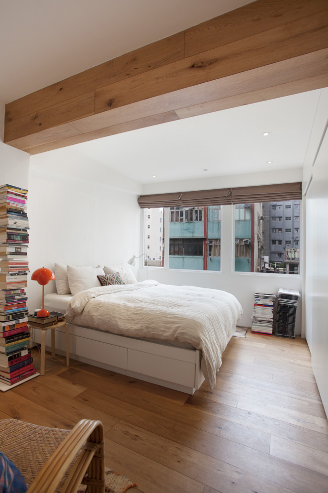 Cette photo montre une chambre tendance avec un mur blanc, un sol en bois brun et un sol marron.