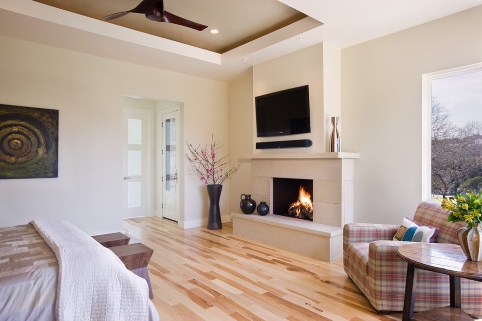 Aménagement d'une chambre parentale contemporaine avec un mur blanc, un sol en bois brun, une cheminée standard et un manteau de cheminée en pierre.
