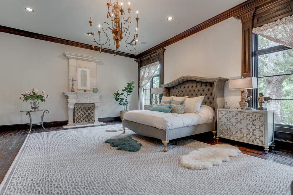 Inspiration for a large mediterranean master bedroom in Dallas with white walls, dark hardwood flooring, a standard fireplace and a stone fireplace surround.