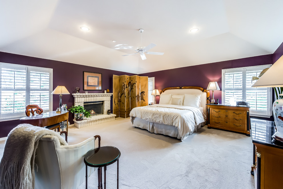 Идея дизайна: большая хозяйская спальня в стиле неоклассика (современная классика) с фиолетовыми стенами, ковровым покрытием, стандартным камином и фасадом камина из кирпича
