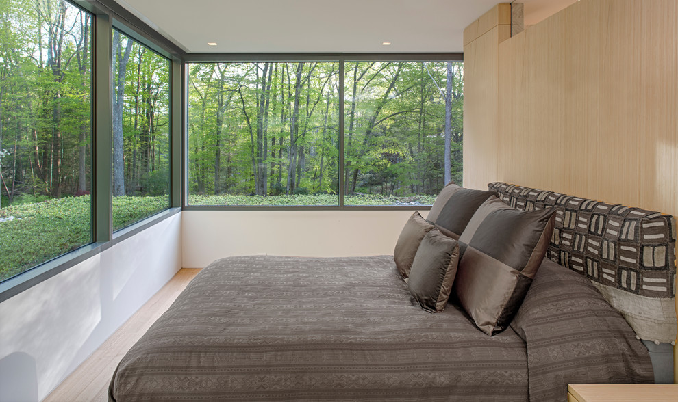 Foto de dormitorio moderno con suelo de madera clara y marco de chimenea de piedra