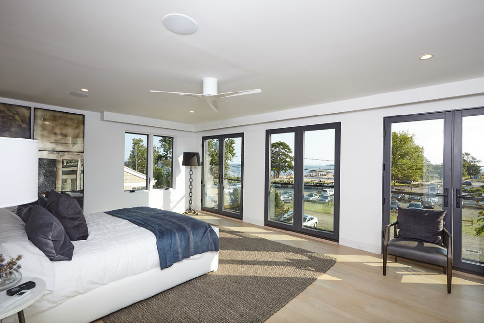 Diseño de dormitorio principal minimalista de tamaño medio con paredes blancas, suelo de madera clara y suelo beige