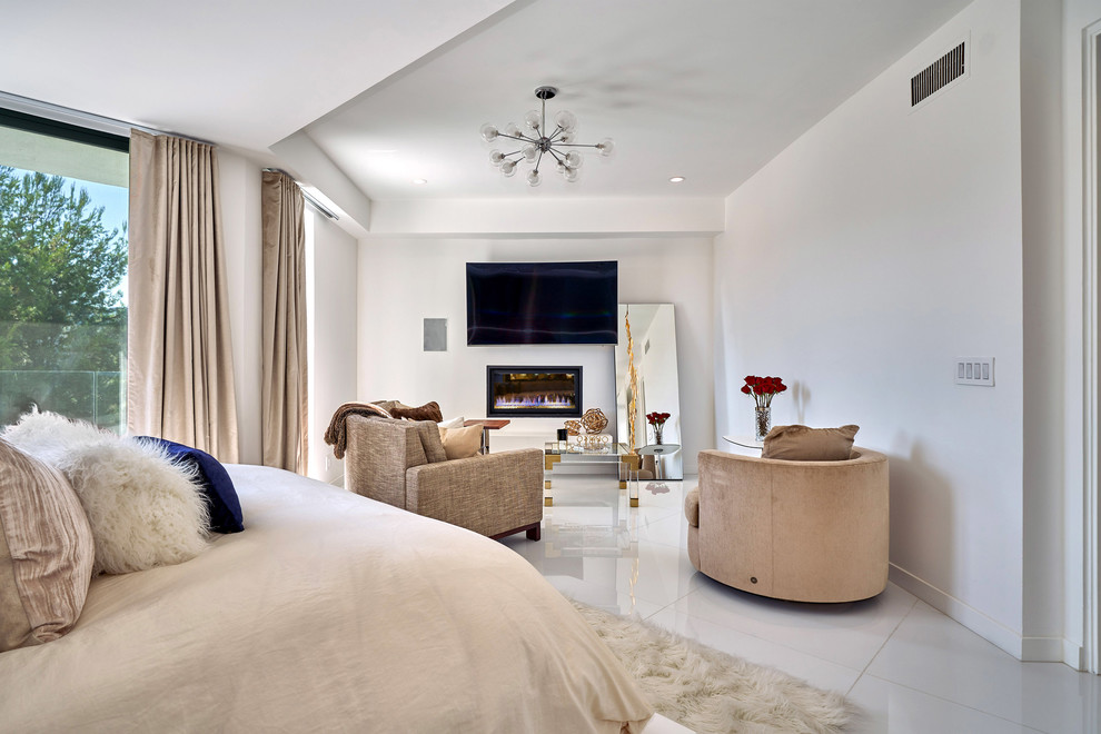 Photo of a contemporary bedroom in Los Angeles with white walls, a standard fireplace and white floors.