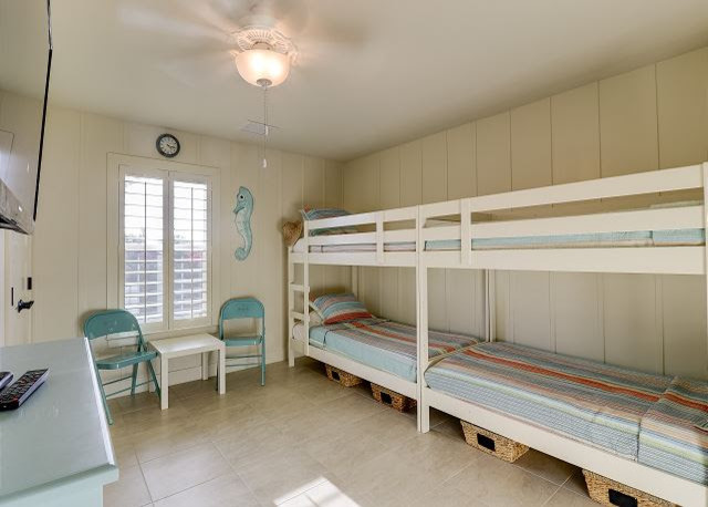 マイアミにある中くらいなビーチスタイルのおしゃれな客用寝室 (ベージュの壁、セラミックタイルの床、暖炉なし、ベージュの床) のインテリア