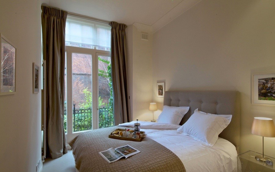 Photo of a medium sized modern master bedroom in London with beige walls and carpet.