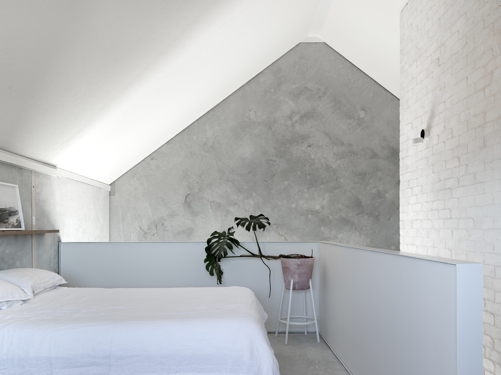 Inspiration pour une chambre mansardée ou avec mezzanine minimaliste avec un mur gris, sol en béton ciré et un sol gris.