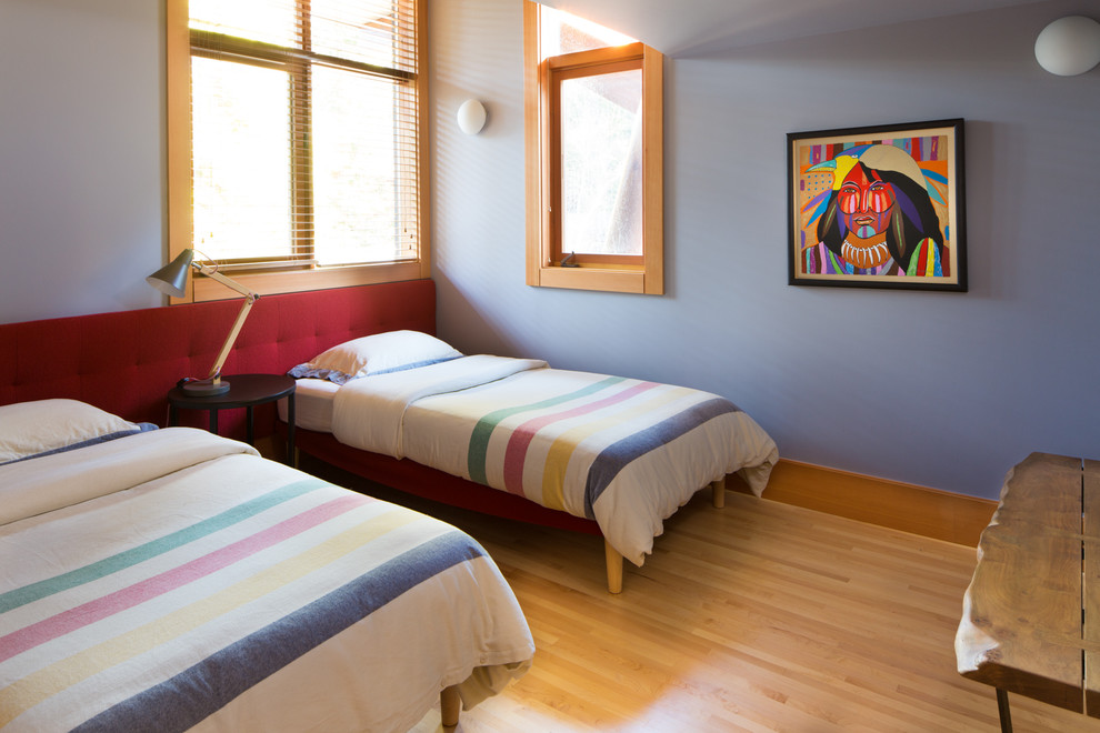 Ejemplo de habitación de invitados moderna de tamaño medio sin chimenea con paredes grises, suelo de madera clara y suelo marrón