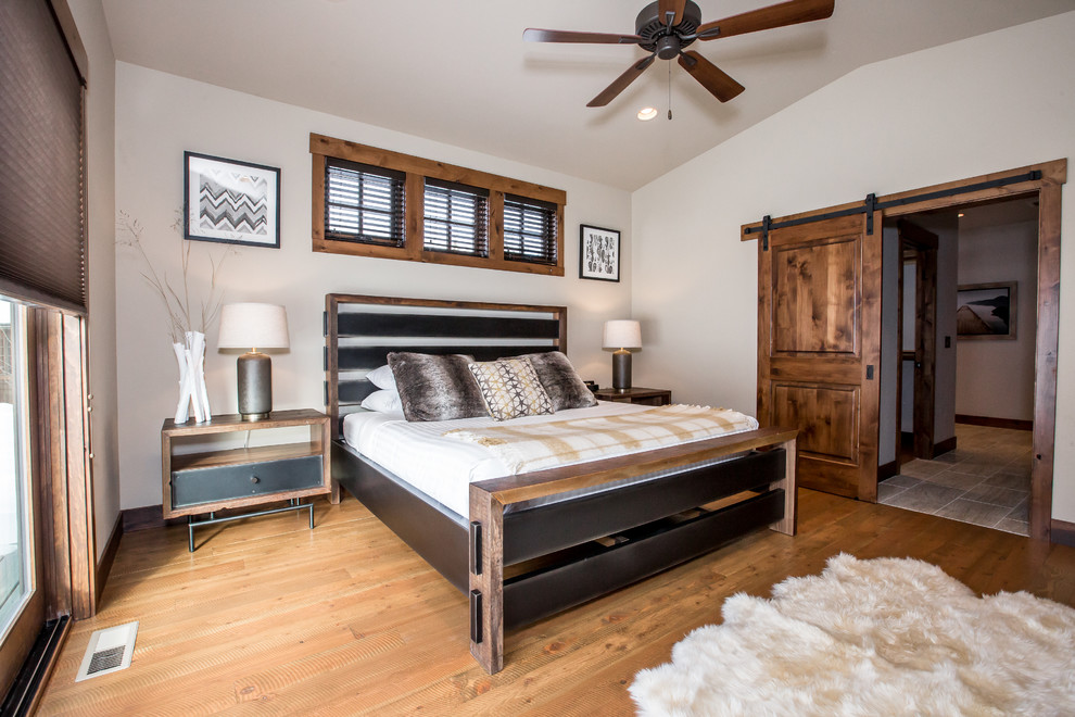 Example of a mid-sized mountain style master medium tone wood floor and brown floor bedroom design in Other with beige walls and no fireplace
