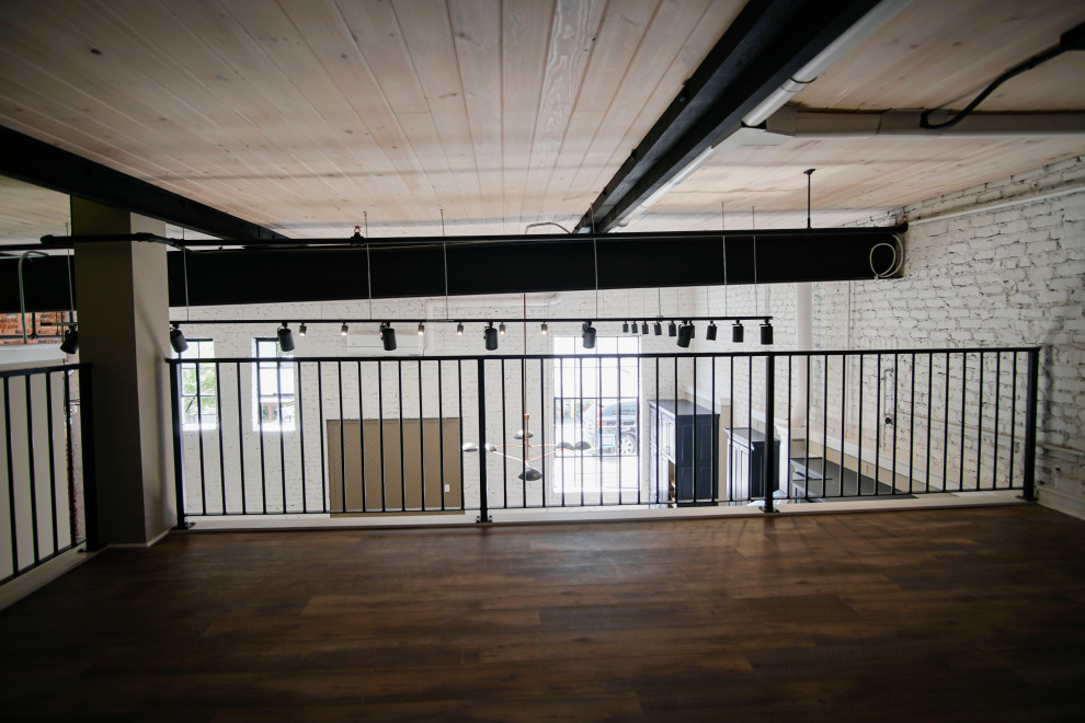 Foto di una camera degli ospiti industriale di medie dimensioni con pareti bianche, pavimento in vinile, nessun camino, pavimento marrone, soffitto in legno e pareti in mattoni