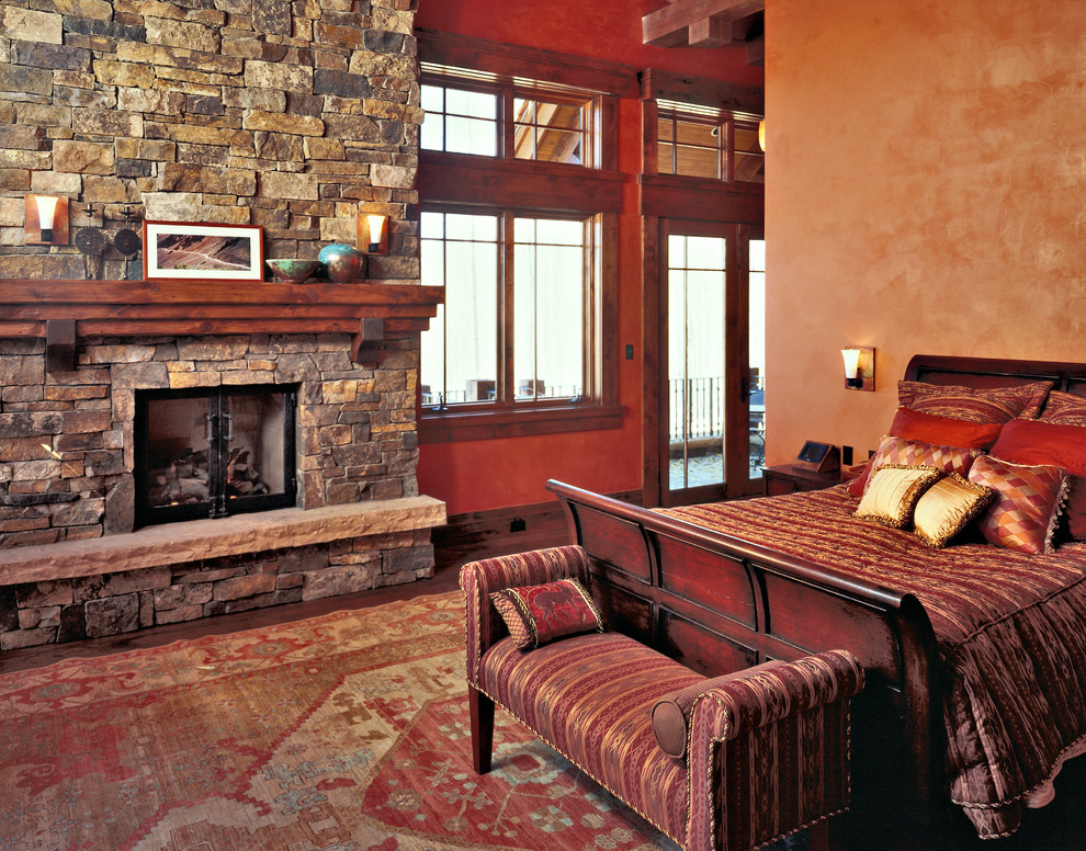 Foto de dormitorio principal minimalista extra grande con paredes marrones, suelo de madera en tonos medios, todas las chimeneas y marco de chimenea de piedra