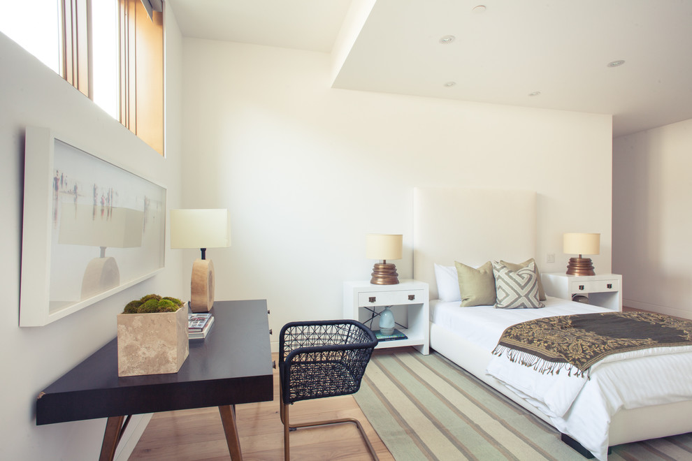 Foto di una camera da letto design con pareti bianche, pavimento in legno massello medio e angolo studio