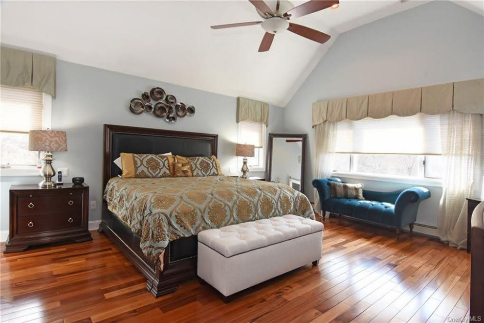 Imagen de dormitorio principal clásico renovado grande con paredes azules y suelo de madera en tonos medios