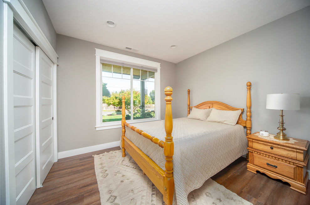 Imagen de habitación de invitados tradicional renovada de tamaño medio sin chimenea con paredes grises, suelo de madera en tonos medios y suelo marrón
