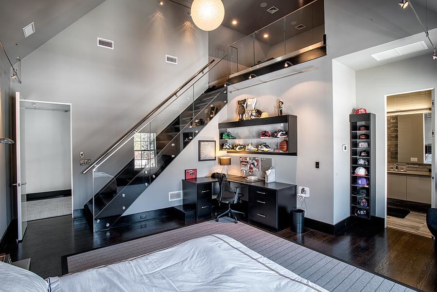 Expansive contemporary mezzanine and grey and brown bedroom in New York with dark hardwood flooring, no fireplace, grey walls and brown floors.
