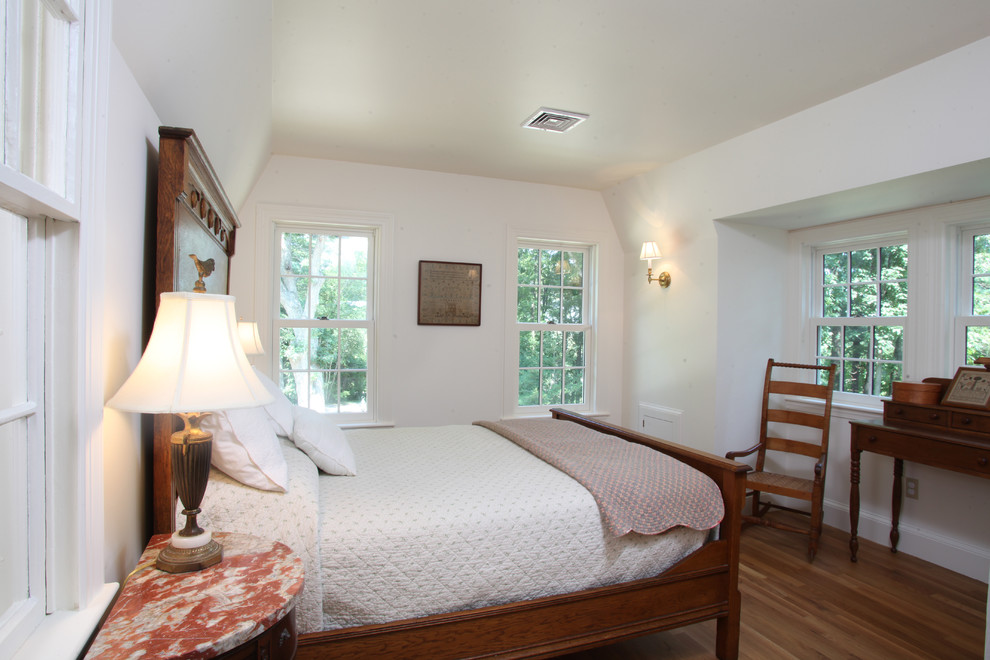 Bild på ett vintage sovrum, med vita väggar och mellanmörkt trägolv