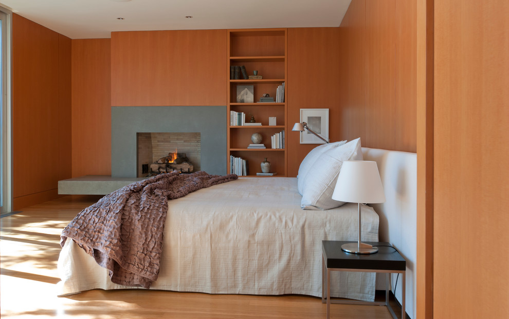 На фото: хозяйская спальня в современном стиле с светлым паркетным полом, стандартным камином, фасадом камина из бетона и коричневыми стенами
