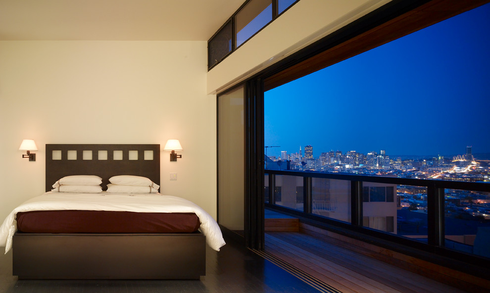 This is an example of a contemporary bedroom in San Francisco with beige walls and dark hardwood flooring.