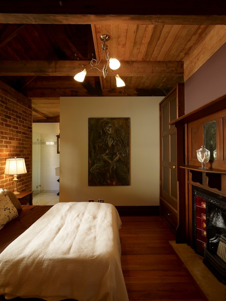 На фото: хозяйская спальня среднего размера в стиле фьюжн с коричневыми стенами, паркетным полом среднего тона, стандартным камином и фасадом камина из дерева