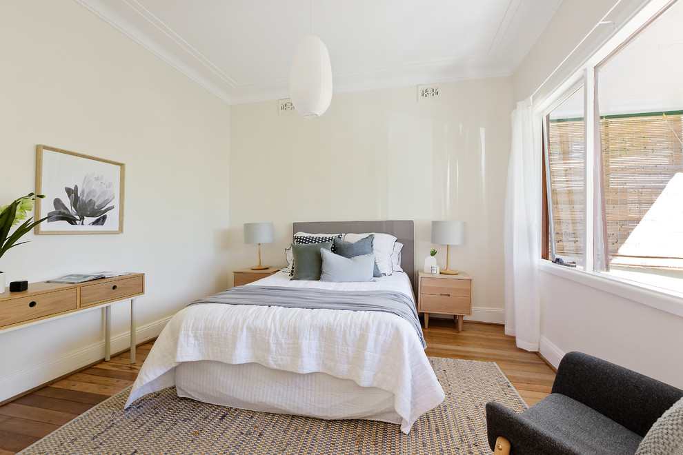 Imagen de dormitorio principal costero de tamaño medio con paredes blancas y suelo de madera clara