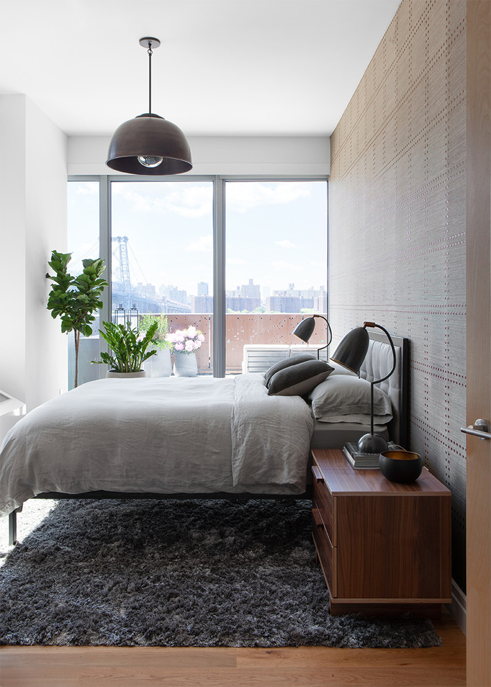 Urban bedroom in New York with white walls, no fireplace, light hardwood flooring and a feature wall.
