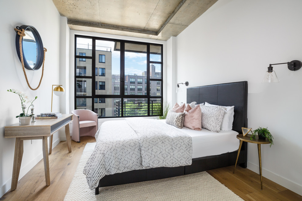 Imagen de habitación de invitados contemporánea de tamaño medio con paredes blancas, suelo de madera clara y suelo marrón
