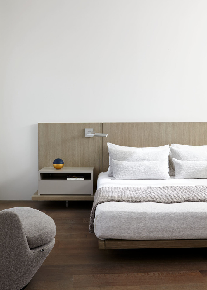Immagine di una camera matrimoniale moderna di medie dimensioni con pareti bianche, pavimento in legno massello medio e pavimento marrone