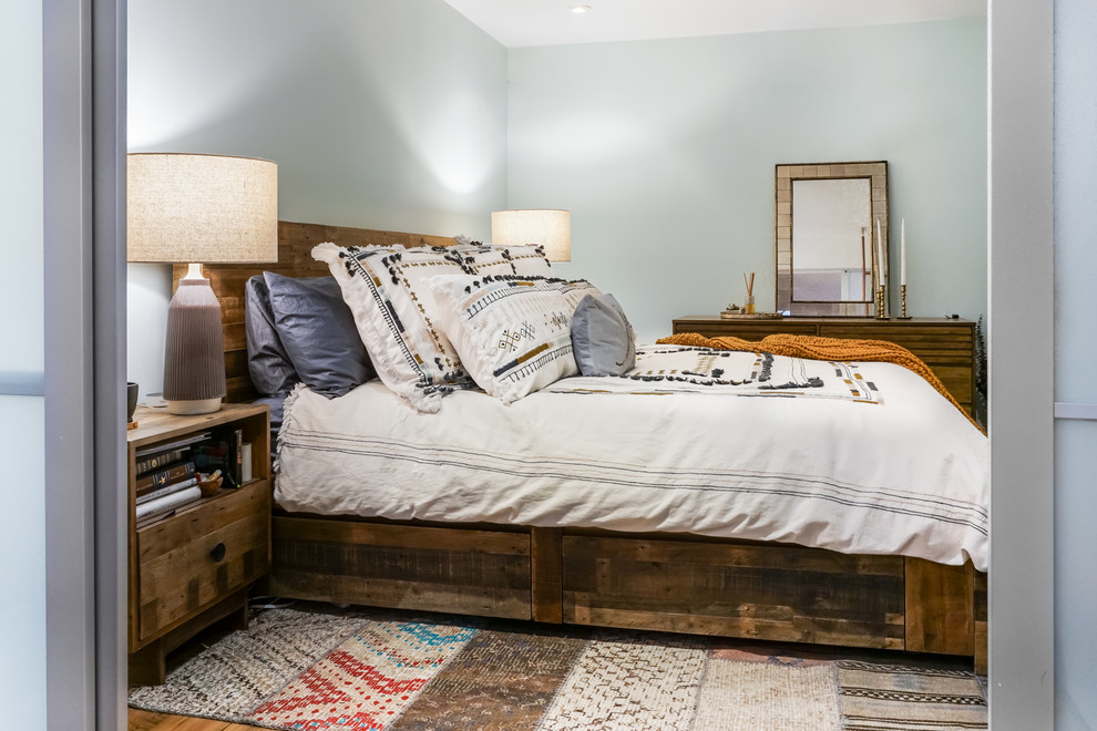 Ejemplo de dormitorio principal rústico de tamaño medio sin chimenea con paredes azules y suelo de madera clara
