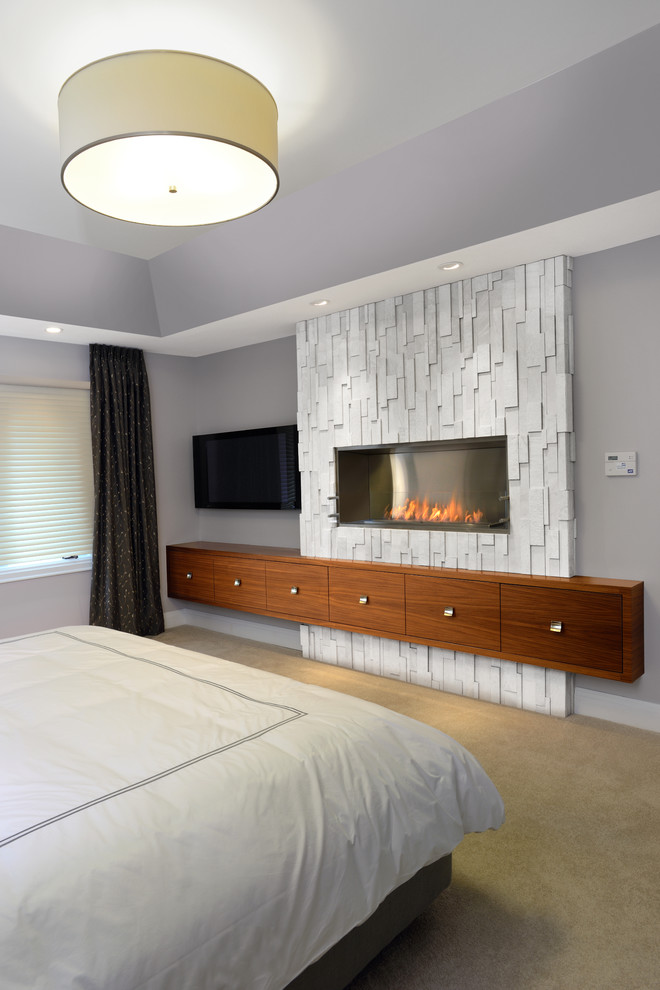 Пример оригинального дизайна: хозяйская спальня среднего размера: освещение в современном стиле с фиолетовыми стенами, ковровым покрытием, горизонтальным камином и фасадом камина из камня