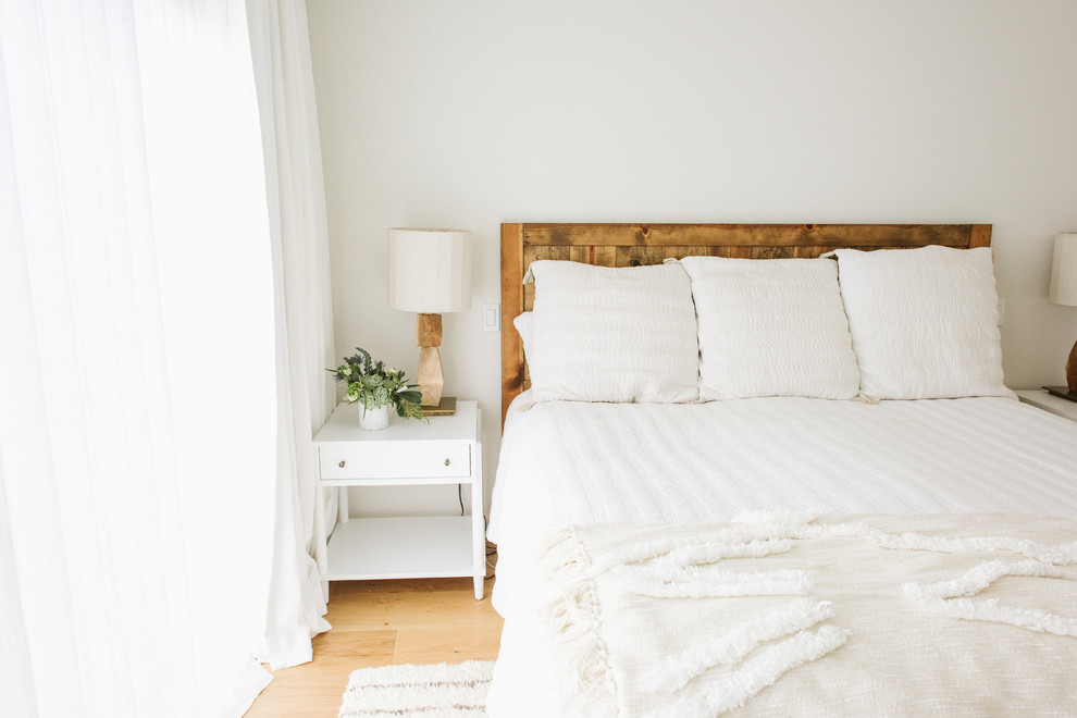 Immagine di una camera matrimoniale boho chic di medie dimensioni con pareti bianche e pavimento in legno massello medio
