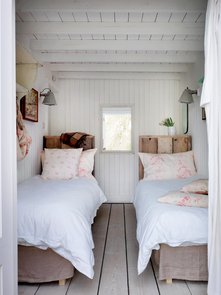 Ejemplo de dormitorio costero con paredes blancas y suelo de madera clara