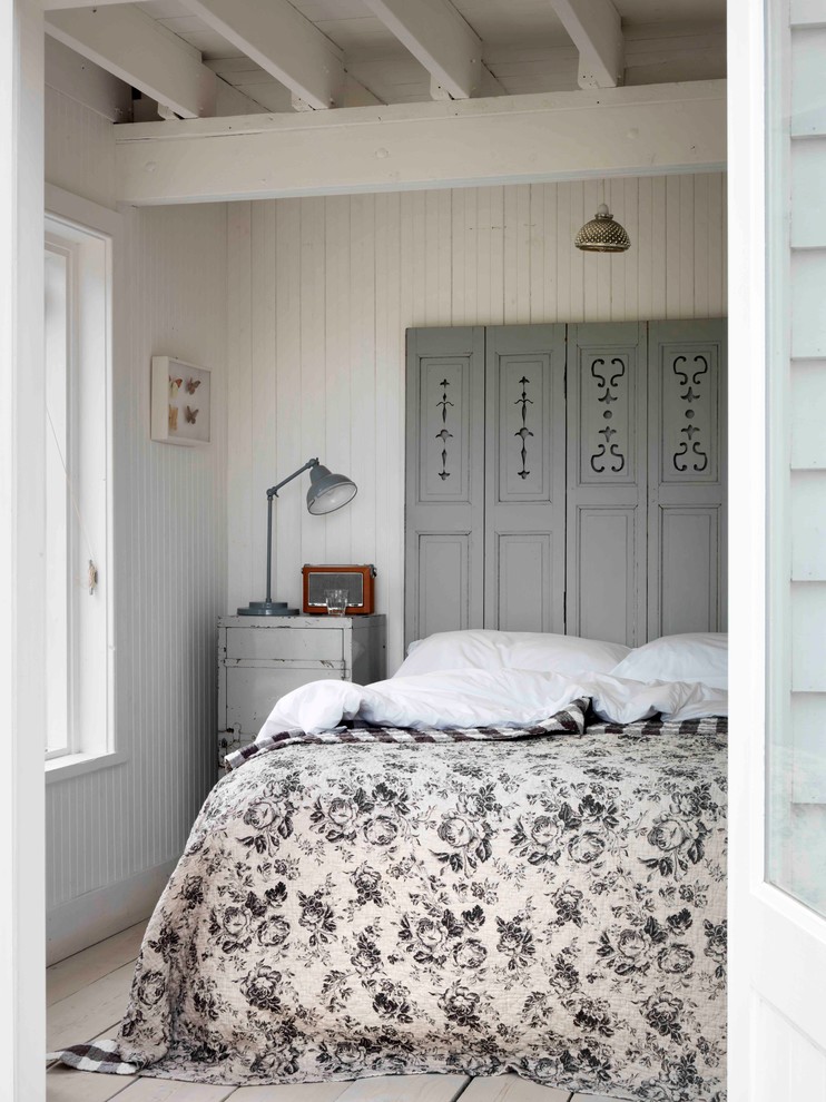 Cottage chic light wood floor bedroom photo in London with white walls