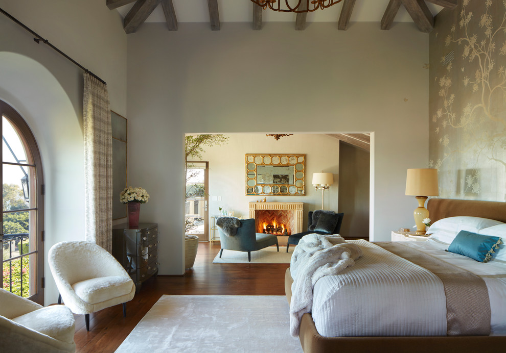 Mediterranes Hauptschlafzimmer mit grauer Wandfarbe, braunem Holzboden, Kamin und braunem Boden in Los Angeles