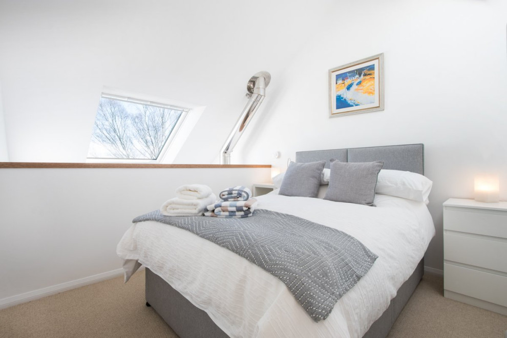 小さなコンテンポラリースタイルのおしゃれなロフト寝室 (白い壁、カーペット敷き、薪ストーブ、石材の暖炉まわり、ベージュの床)