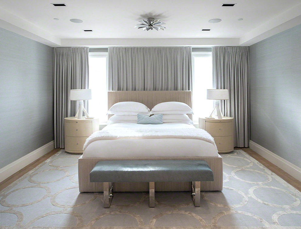 Diseño de dormitorio principal moderno de tamaño medio sin chimenea con paredes azules y suelo de madera clara