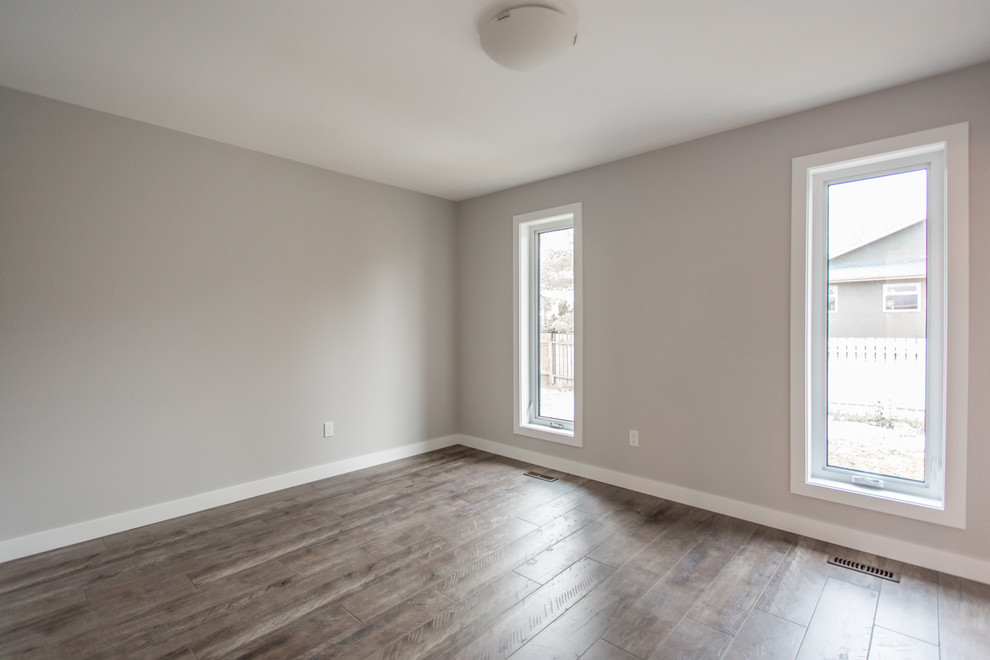 Ejemplo de habitación de invitados minimalista de tamaño medio con paredes grises y suelo de madera en tonos medios