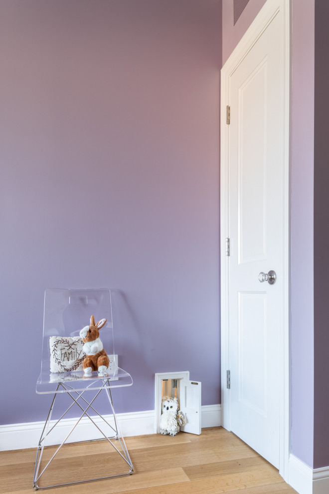 Photo of a small traditional bedroom in New York with purple walls and light hardwood flooring.